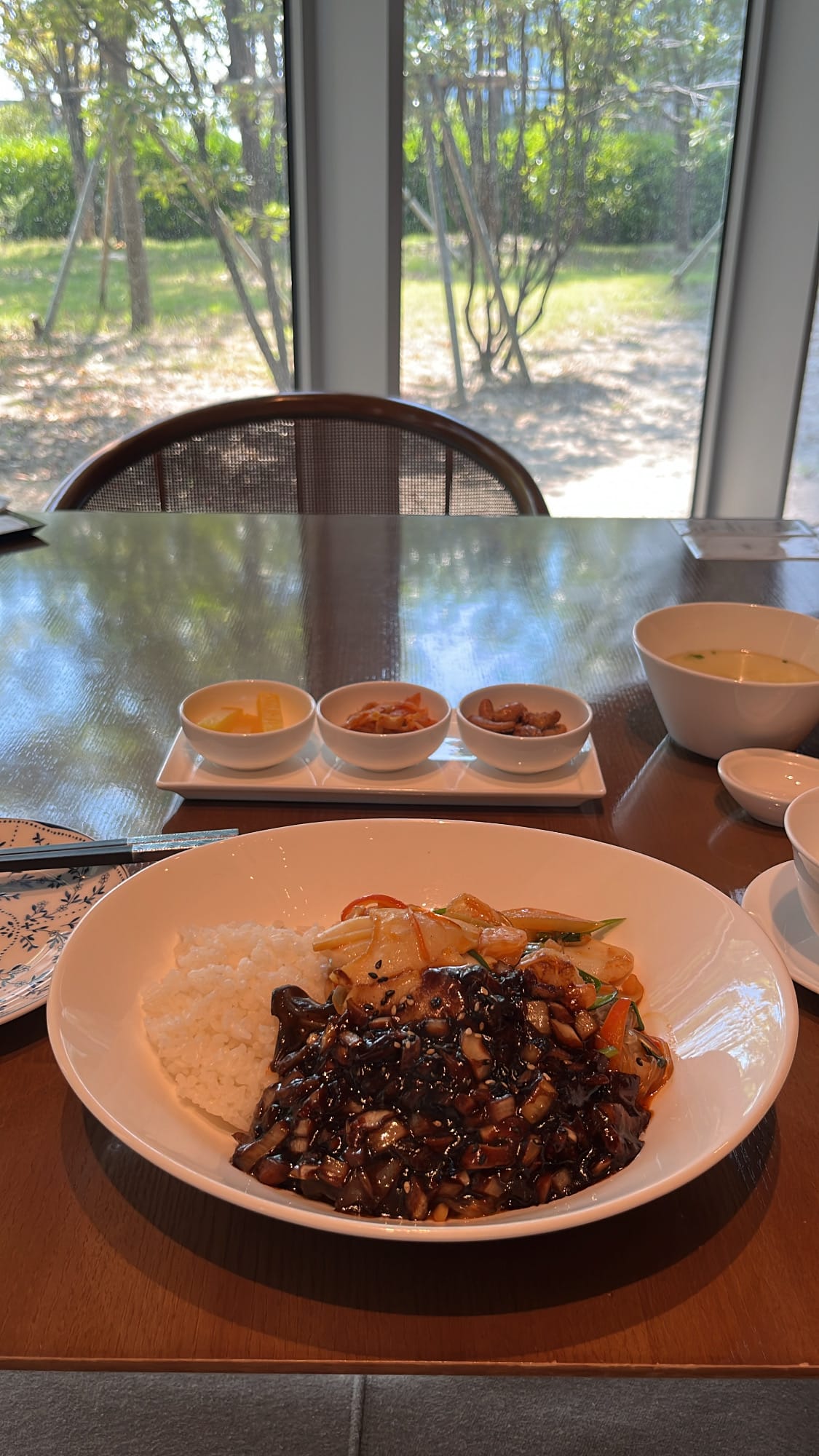 Generous bowl of seafood japchaebap served with black bean sauce and side dishes at Village de Ananti Lou Busan