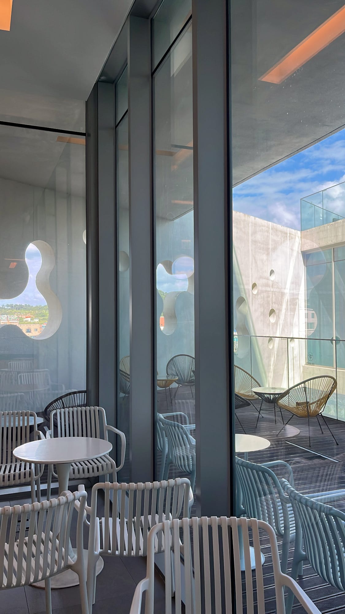 Varied dining chairs and floor-to-ceiling windows inside Coralani Busan