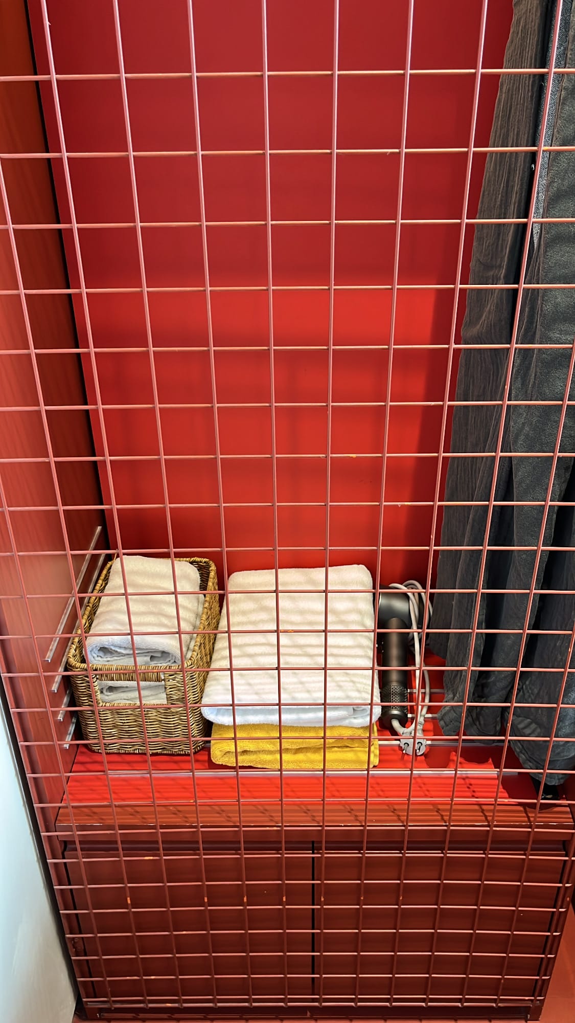 Red industrial mesh wardrobe and amenities storage at The Coolest Hotel