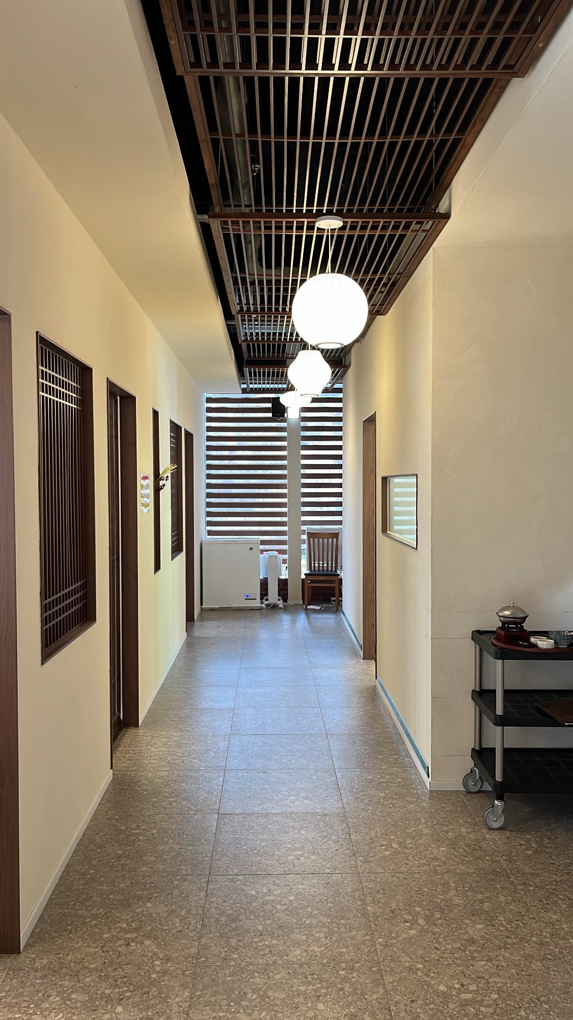 Modern wooden ceiling slats, pendant globes, and private room doors on floor 2 of Unaju Busan