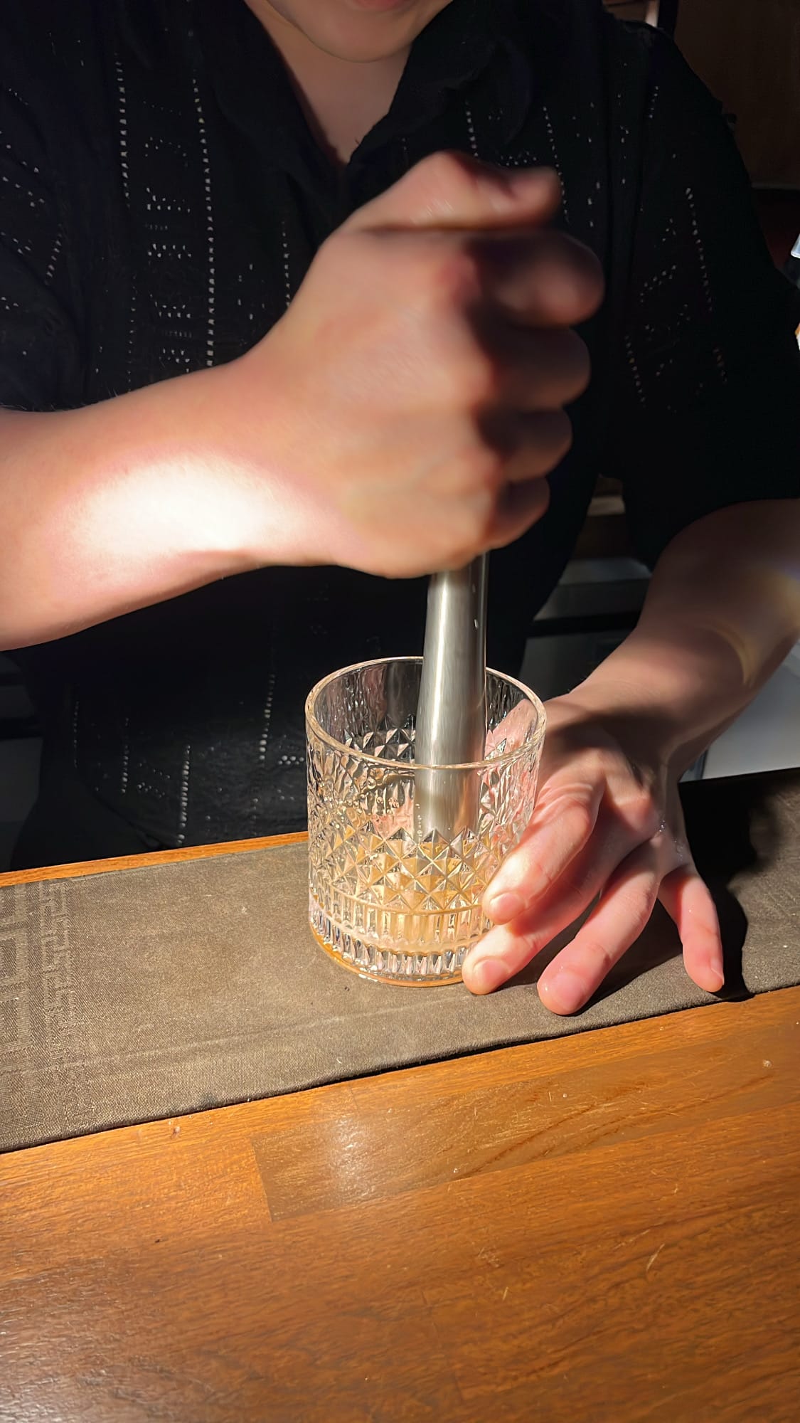 Muddling sugar and bitters in rocks glass for an Old Fashioned