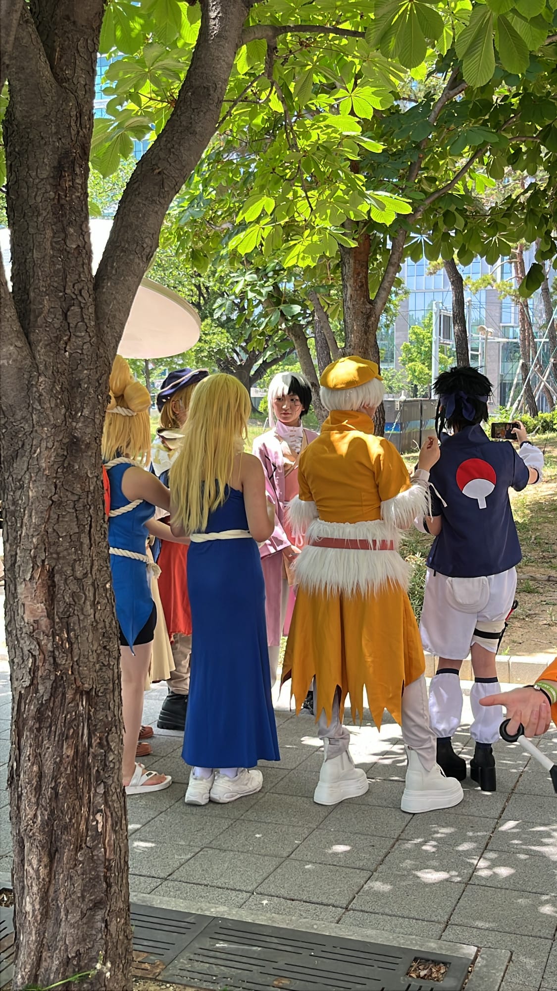 Cosplayers with colorful wigs socializing in BEXCO outdoor park
