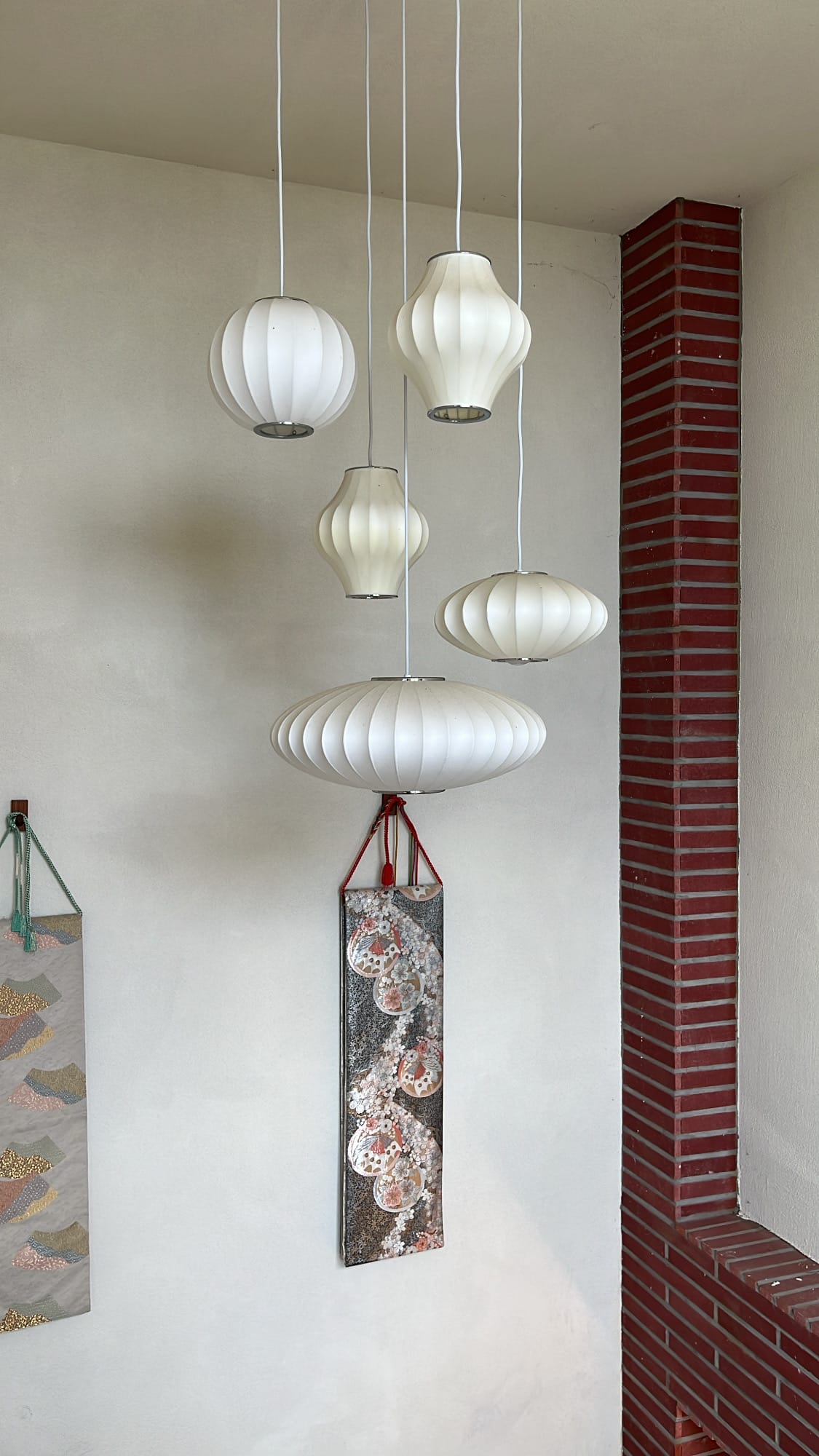 Cluster of Japanese-style ribbed paper pendant lights hanging against the interior brick wall of Unaju Busan