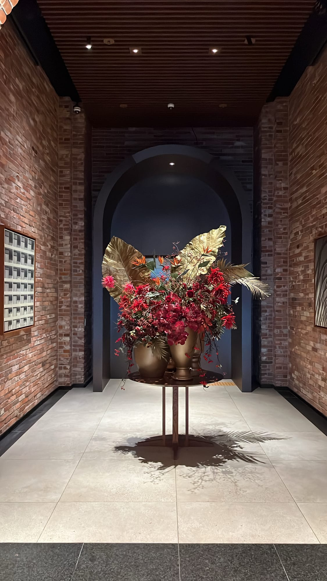 Striking crimson and gold floral sculpture set under a brick arch in the foyer at Village de Ananti Lou Busan