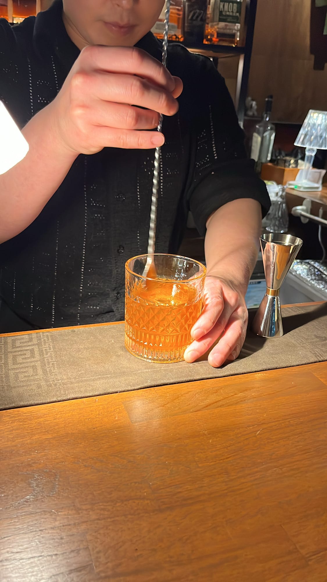 Bartender stirring classic Old Fashioned cocktail with twisted bar spoon