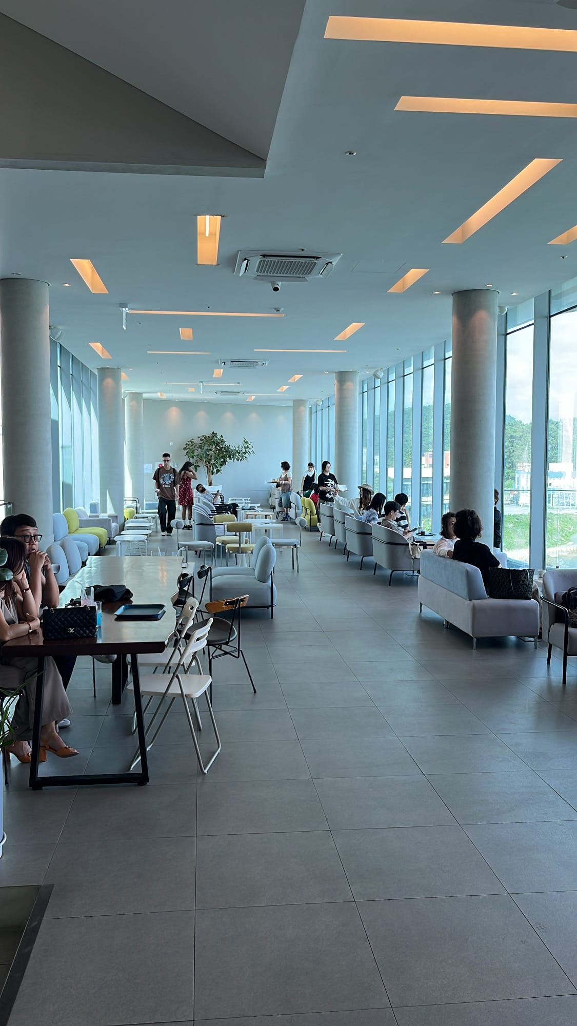 Long upper-floor seating hall lined with panoramic floor-to-ceiling windows at Coralani Busan