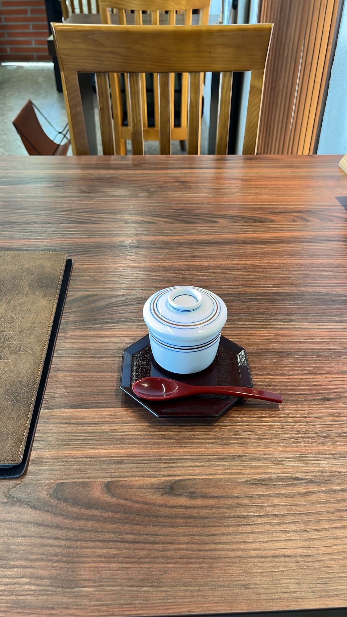 Lidded ceramic bowl of chawanmushi egg custard starter on wooden table at Unaju Busan