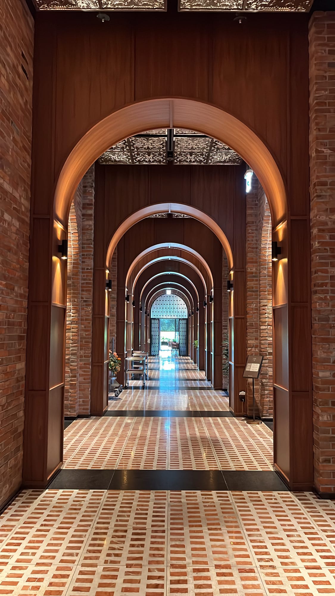 Symmetrical corridor vista of multi-layered brick arches with patterned marble floors at Village de Ananti Lou Busan