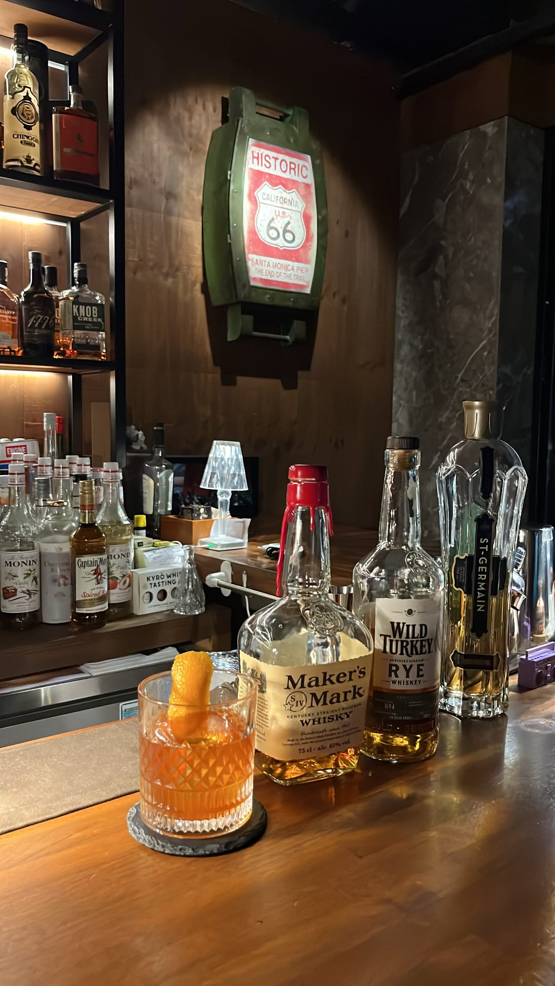 Finished Old Fashioned cocktail garnished with thick fresh orange twist