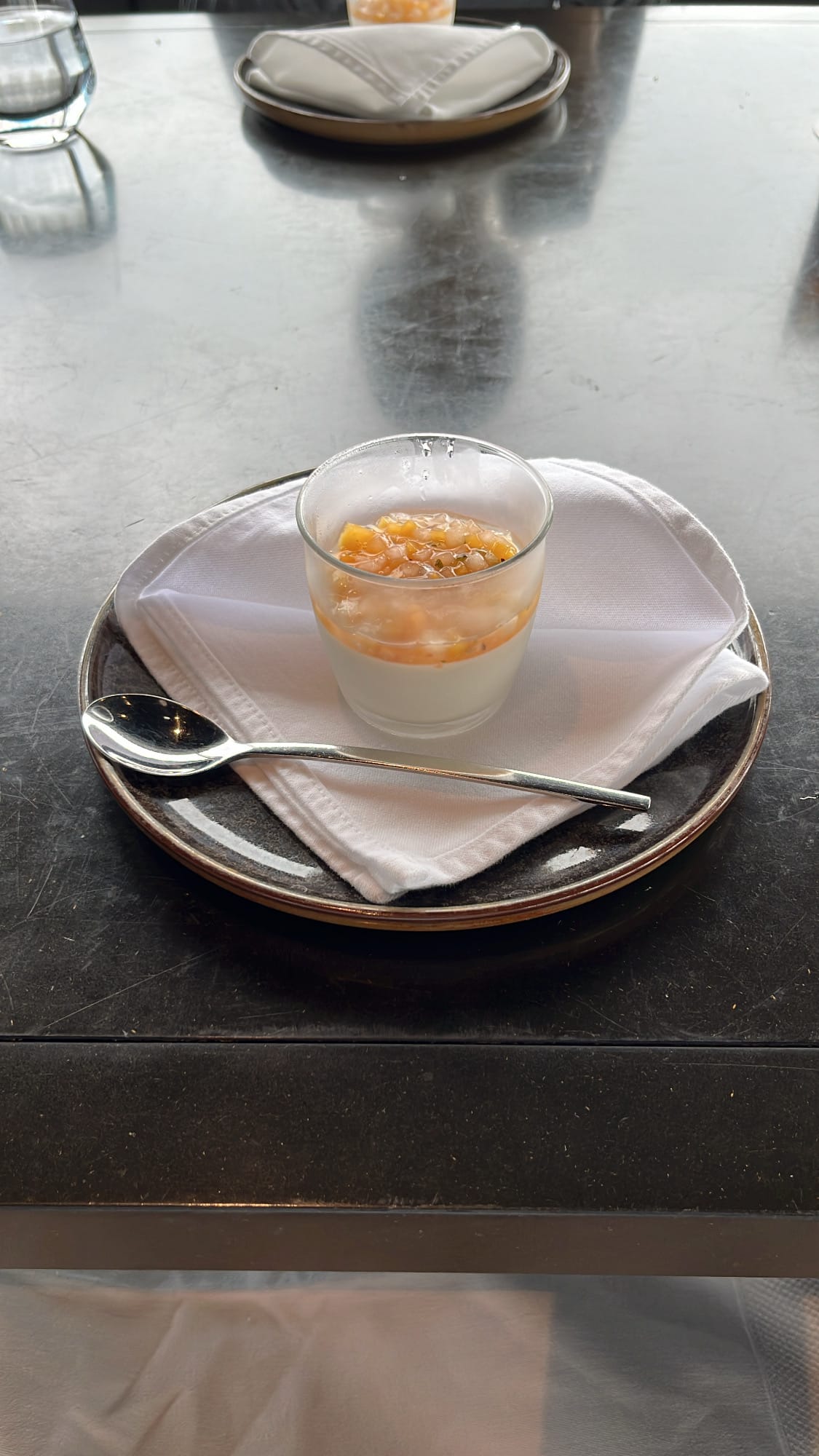 Glass cup of creamy panna cotta dessert placed on a dark saucer