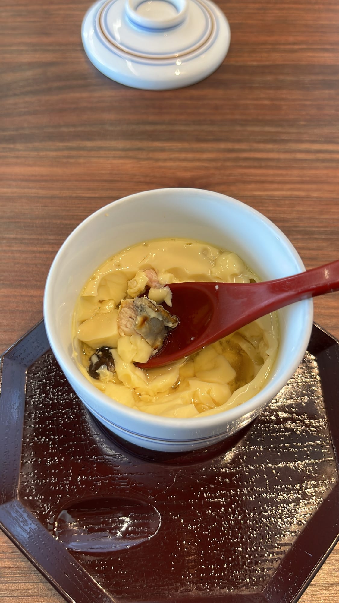 Spoon scooping a piece of tender grilled eel from inside the chawanmushi custard at Unaju Busan