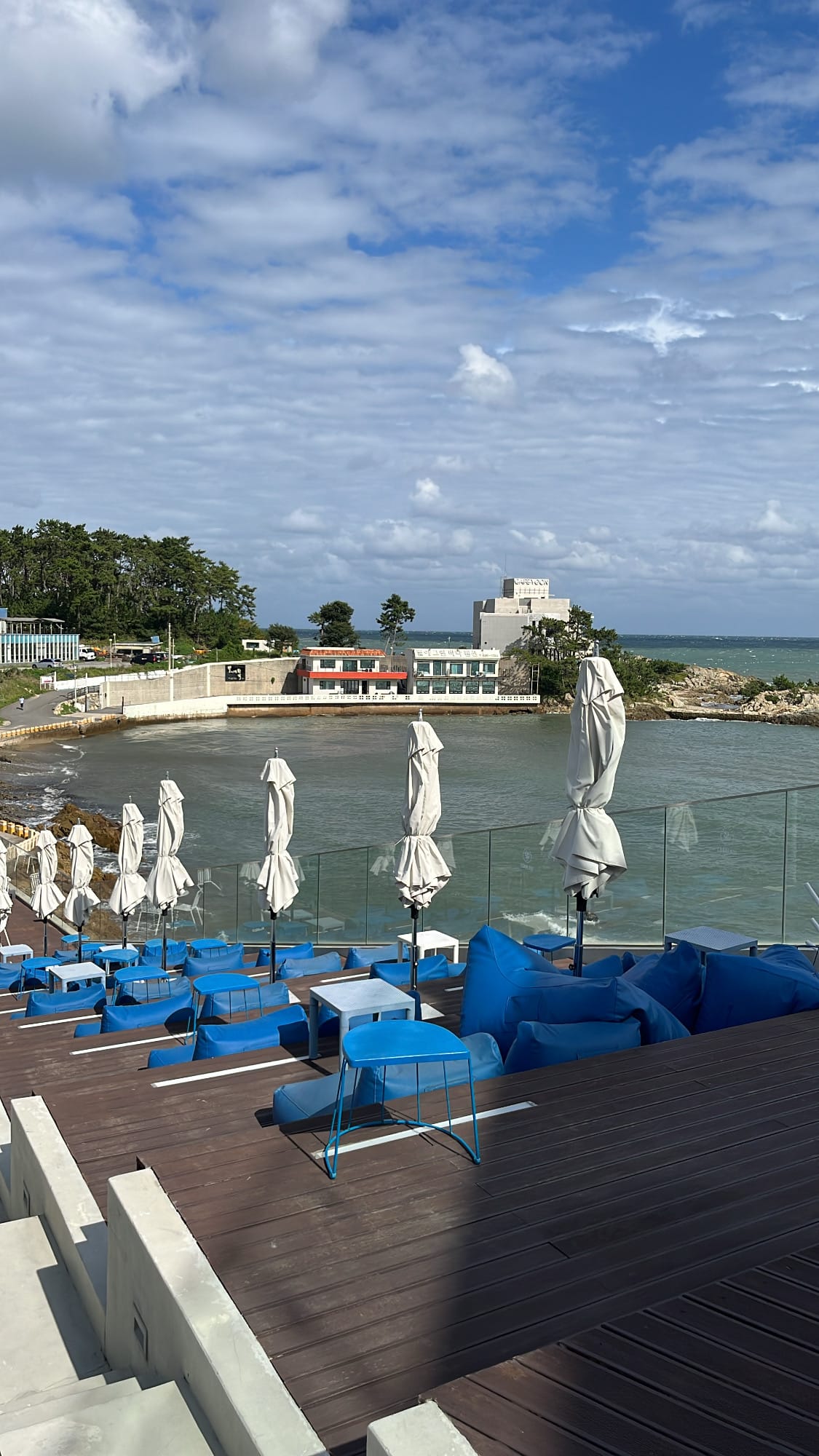 Folded terrace umbrellas and stepped blue beanbags facing the bay at Coralani Busan