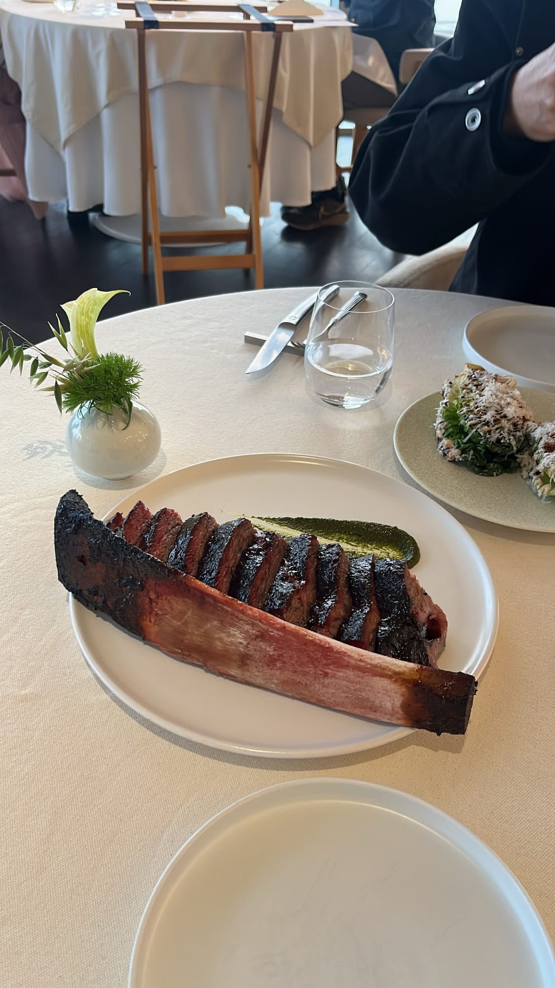 Sliced signature beef rib with bone and green chimichurri sauce