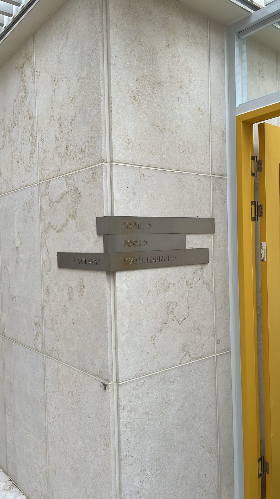 Stone wall directional sign pointing toward rooftop pool and water lounge