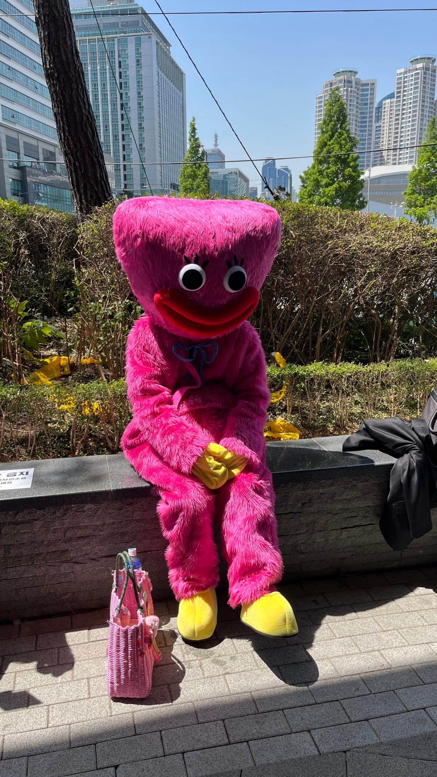 Poppy Playtime Kissy Missy plush costume seated on BEXCO bench