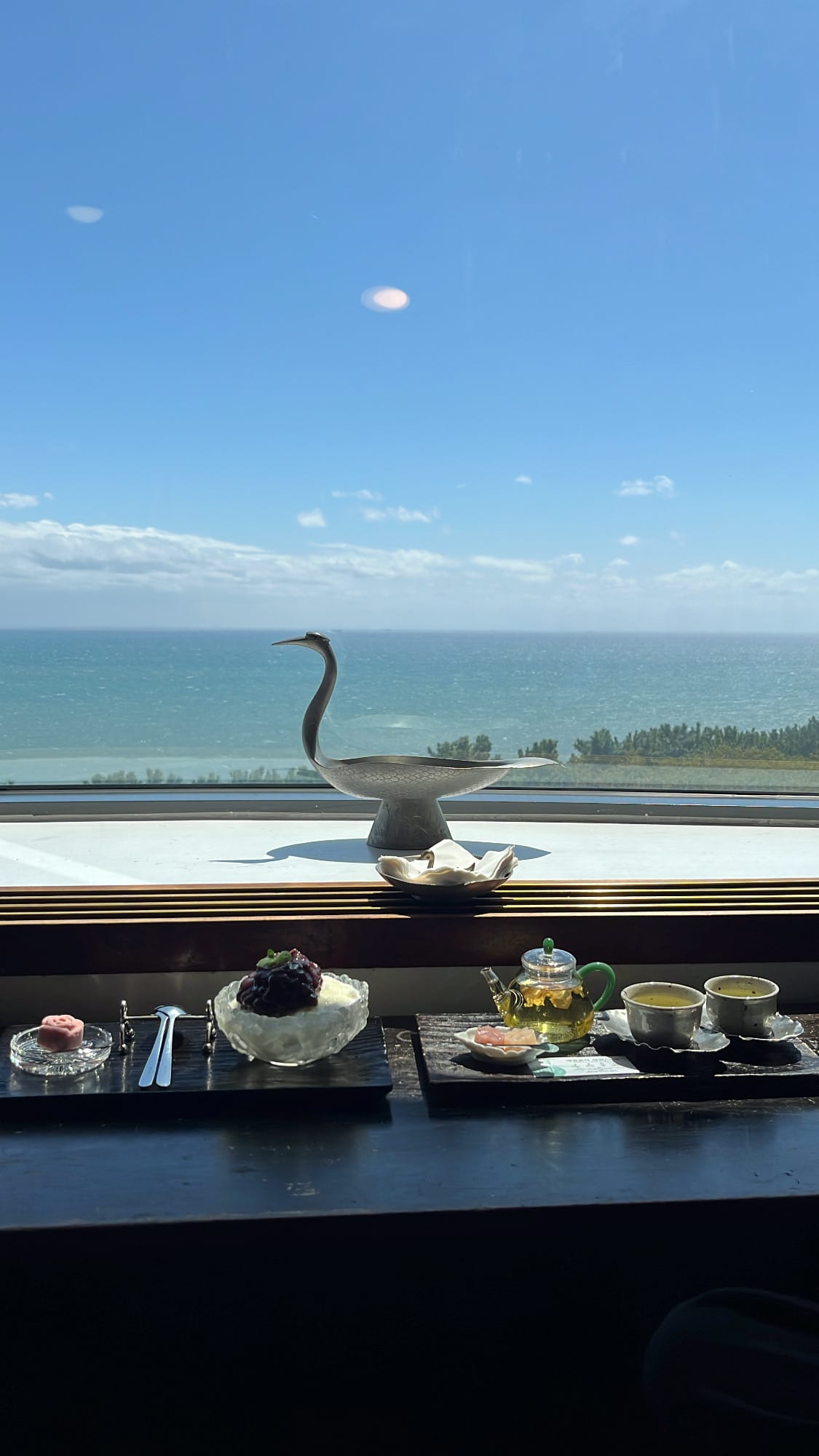 Tray set of Magnolia flower tea and red bean shaved ice on a table with an ocean view