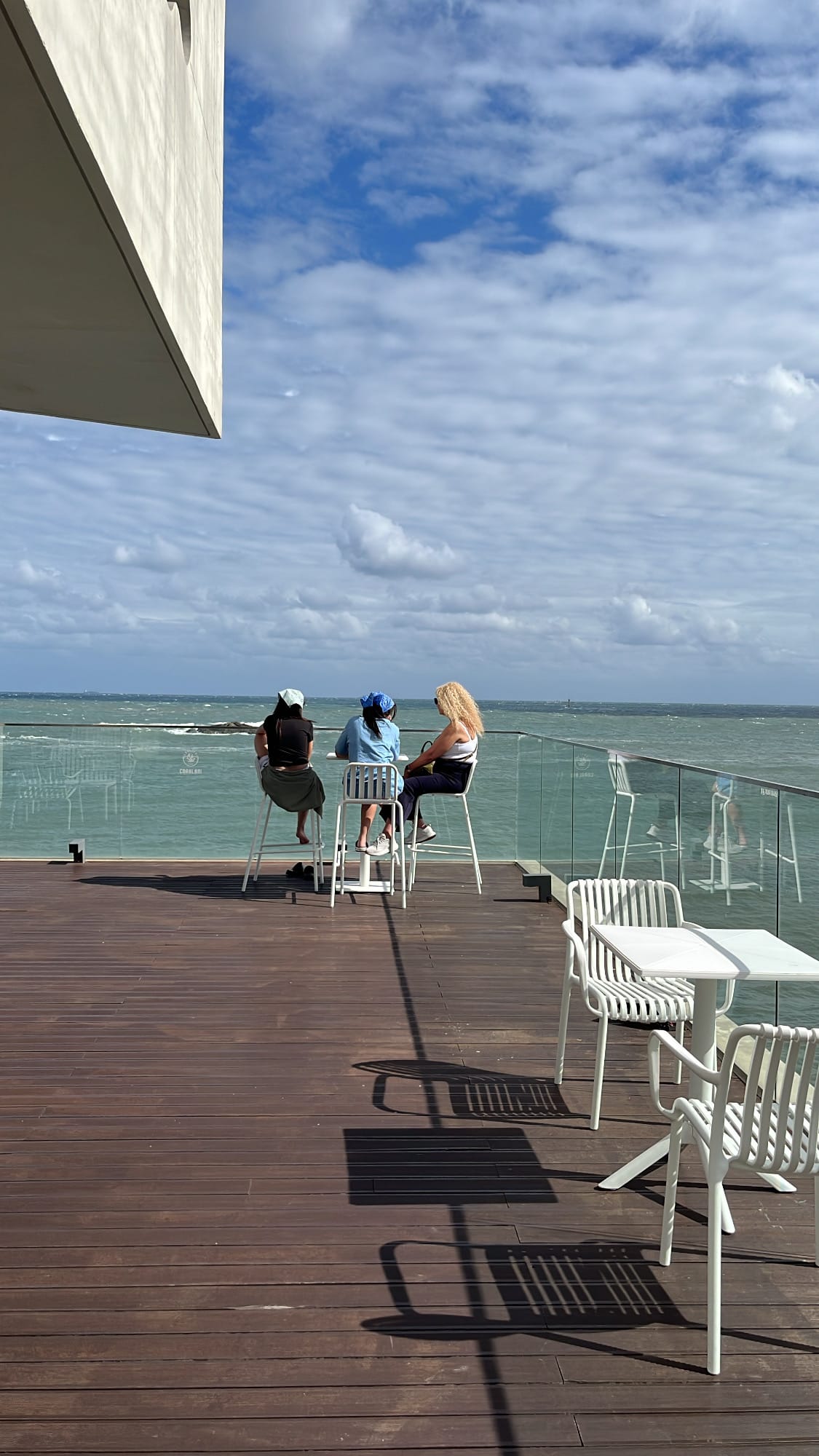 Guests enjoying beverages at high-top tables on the wooden deck of Coralani Busan
