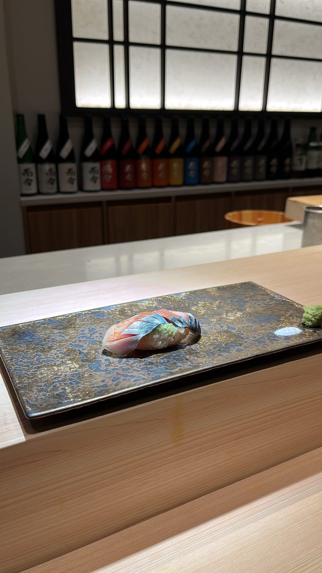 ภาพด้านข้างของซูชิปลาแมคเคอเรลที่หมักแล้วบนจานหินที่ร้าน Sushi Nee Busan