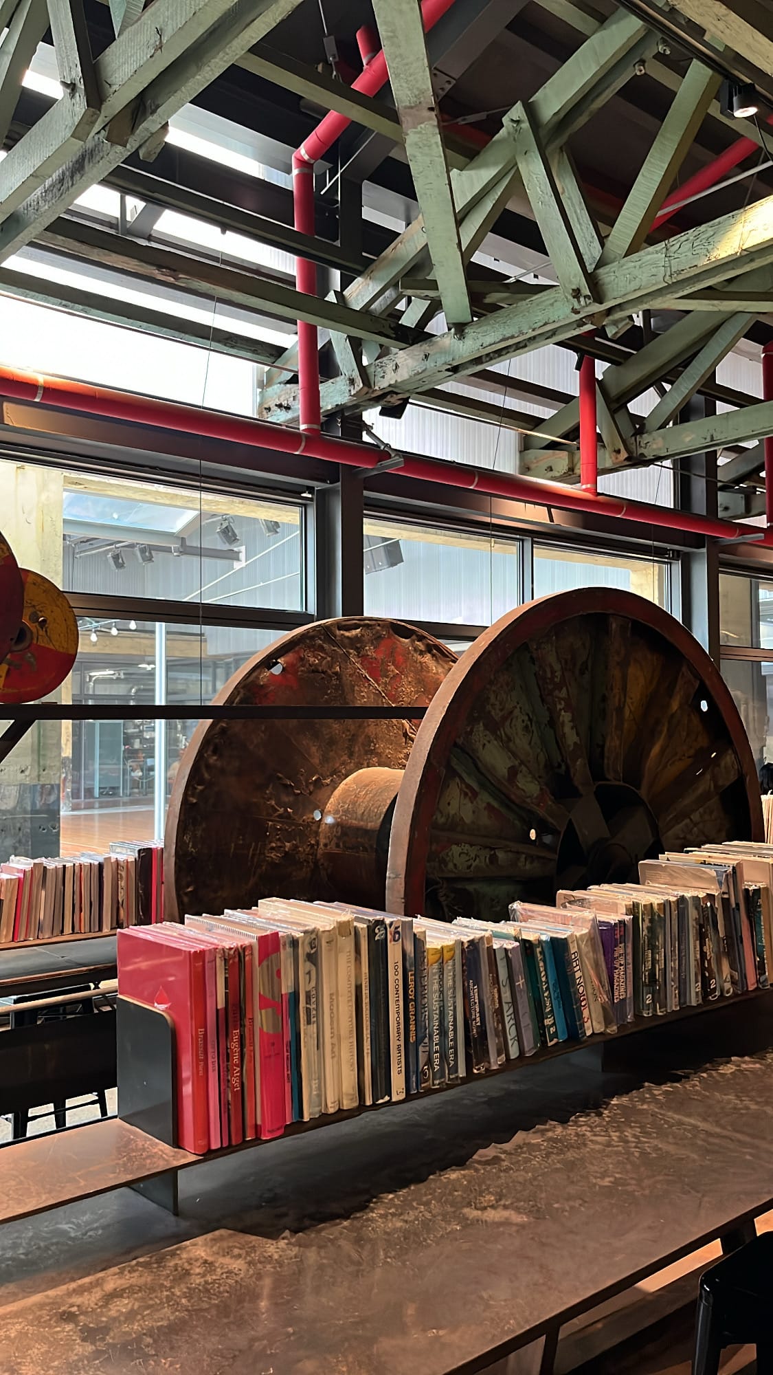 Gigantic rusted factory gear wheel standing behind art book tables