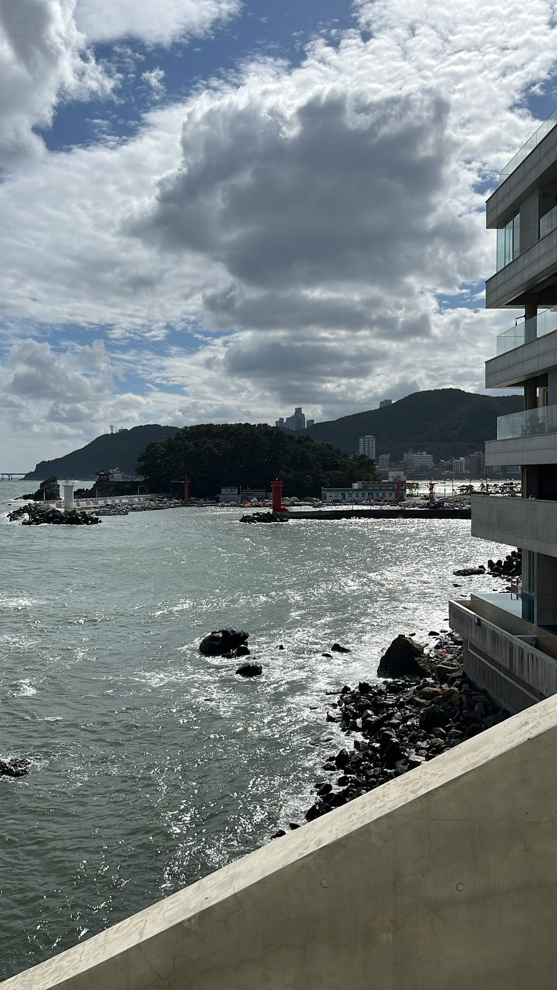 Distant harbor, lighthouses, and rolling hills along the Songjeong coast from Coralani Busan