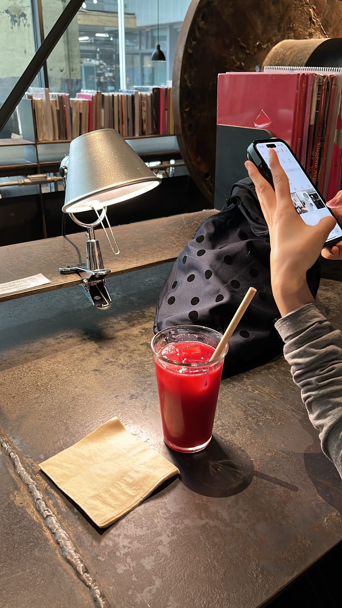 Cold red pressed juice on rustic iron table next to reading lamp and book
