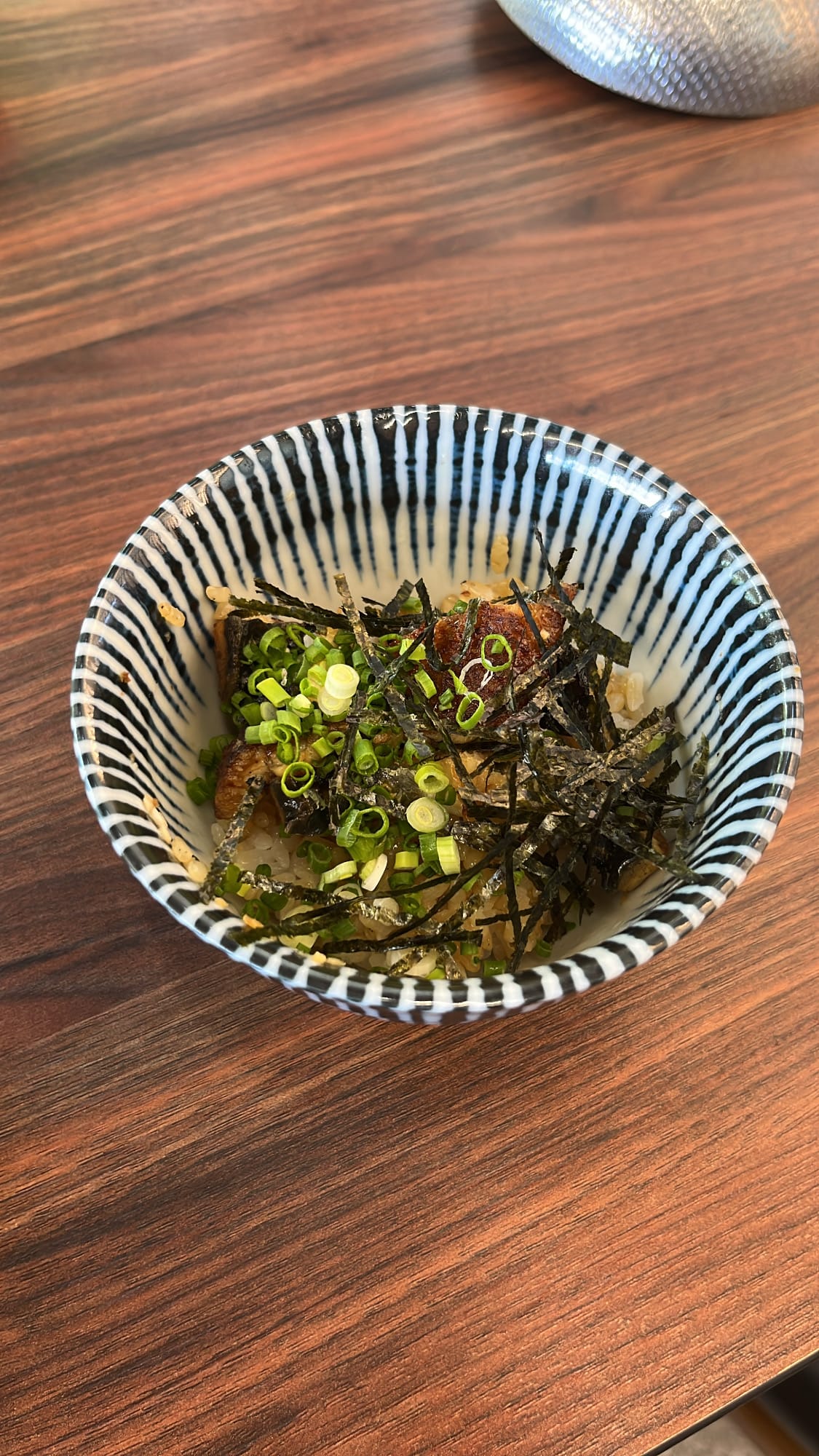 Ceramic bowl portion of eel rice garnished with green onions, wasabi, and shredded nori at Unaju Busan