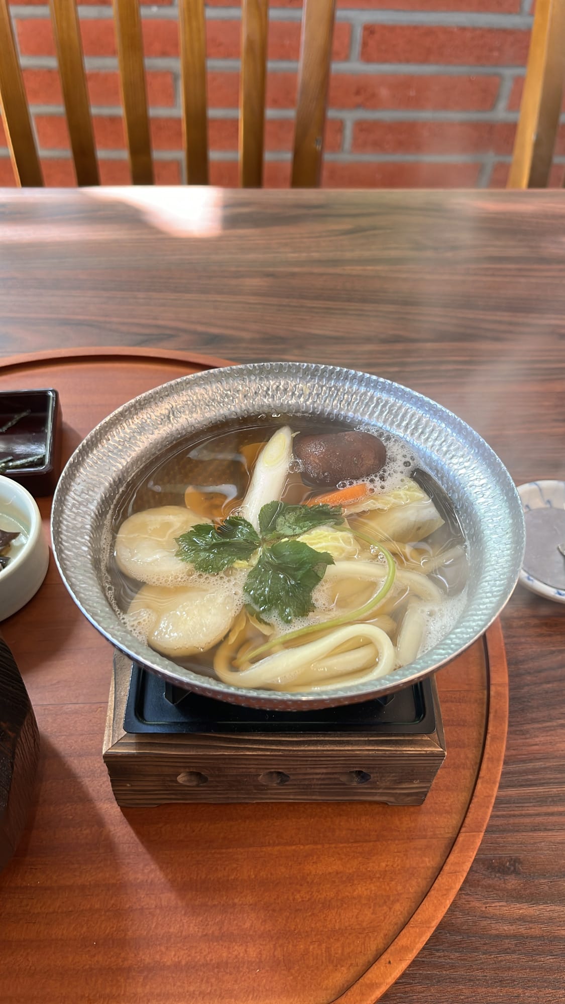Silver tabletop burner pot filled with yosenabe soup, udon noodles, and vegetables at Unaju Busan