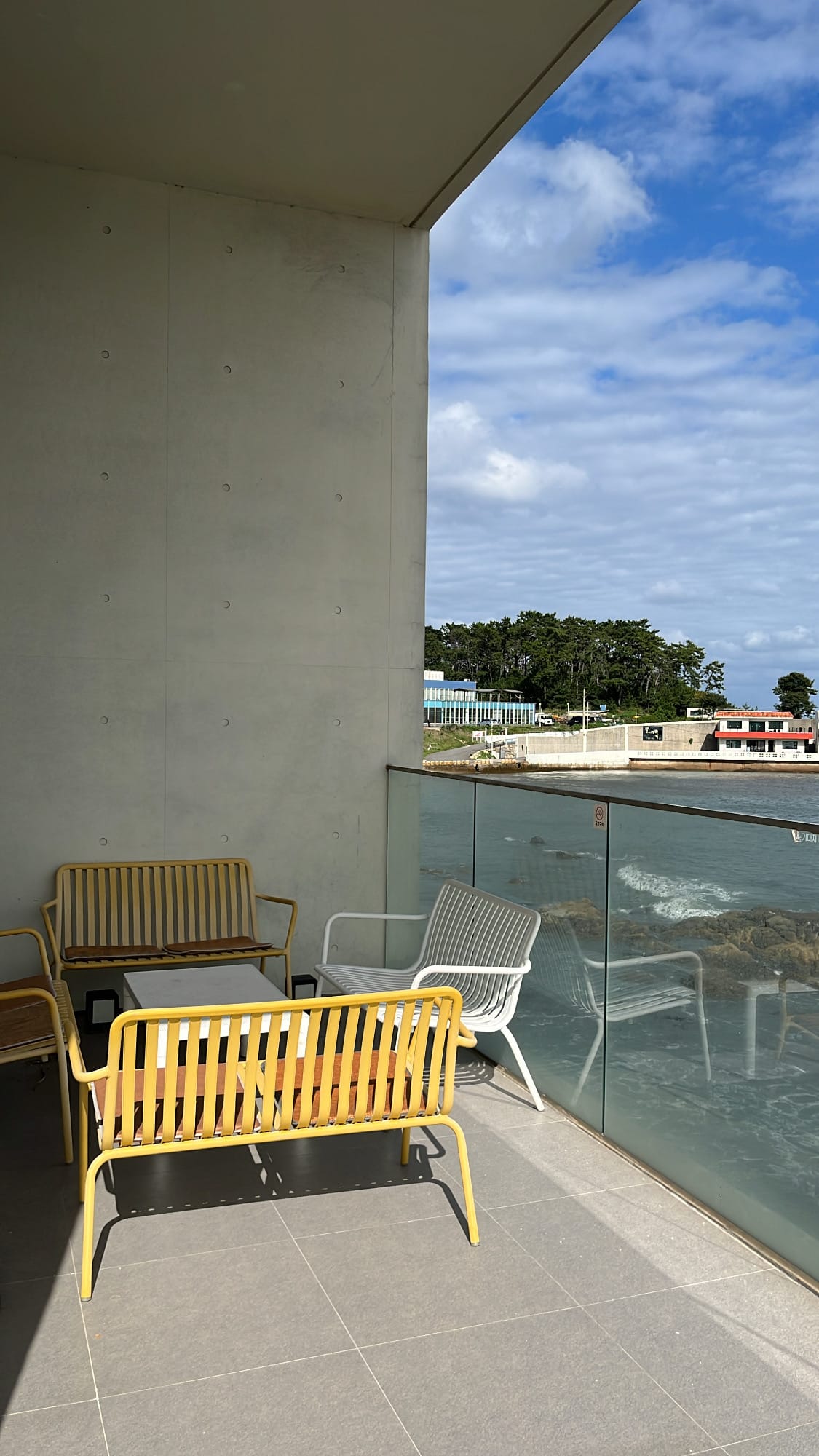 Shaded balcony nook fitted with casual benches overlooking the bay at Coralani Busan