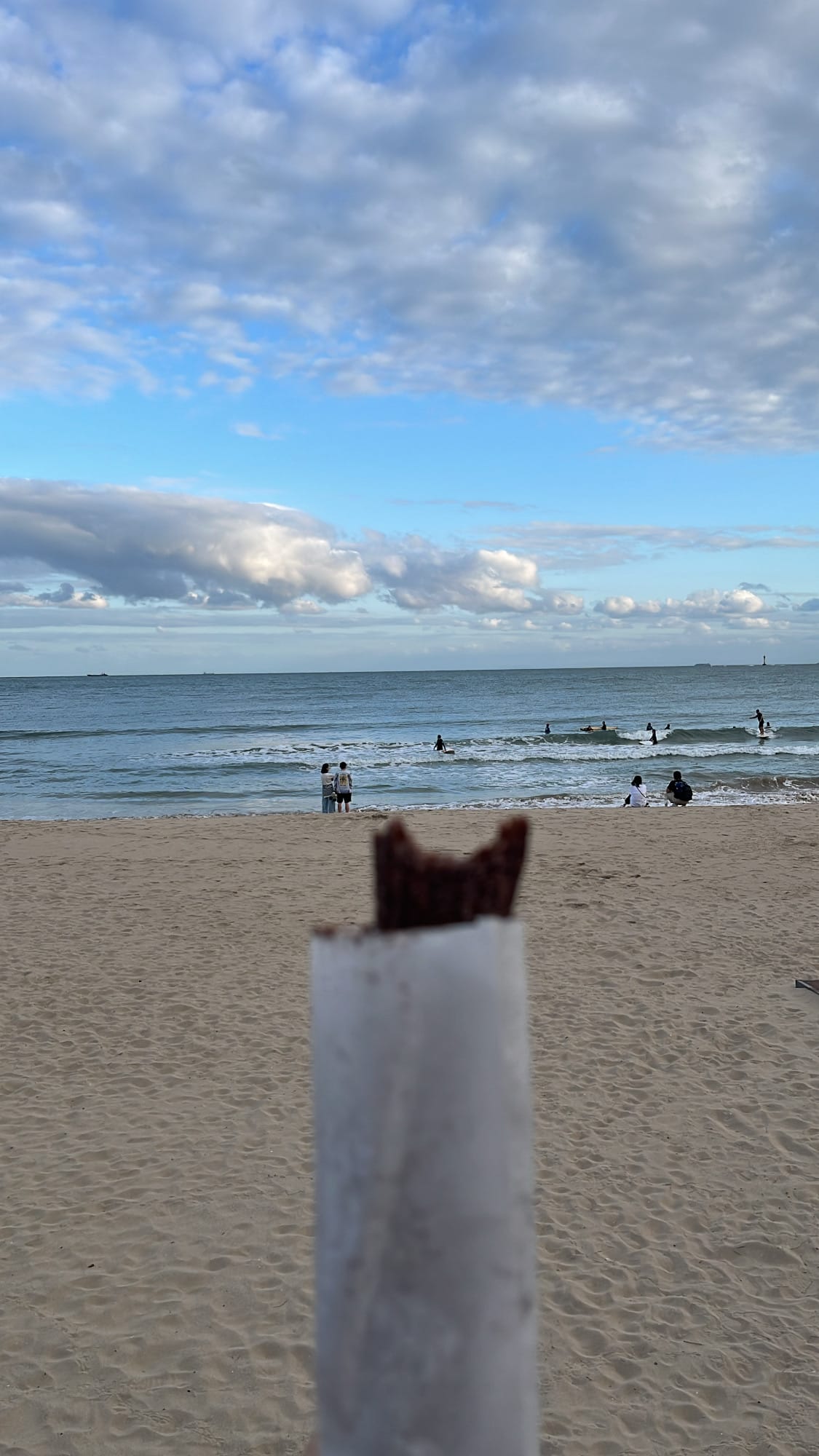 Bitten chocolate churros pointed toward sunny blue ocean waters