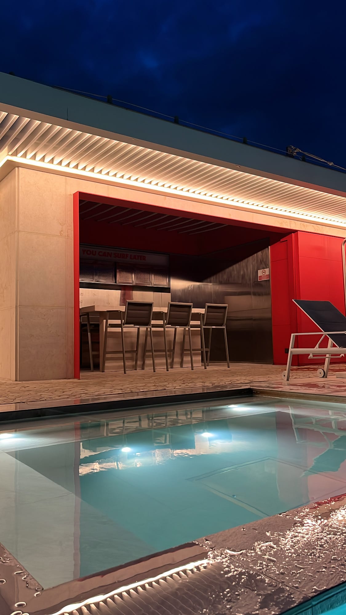 Illuminated rooftop swimming pool and pool bar during evening