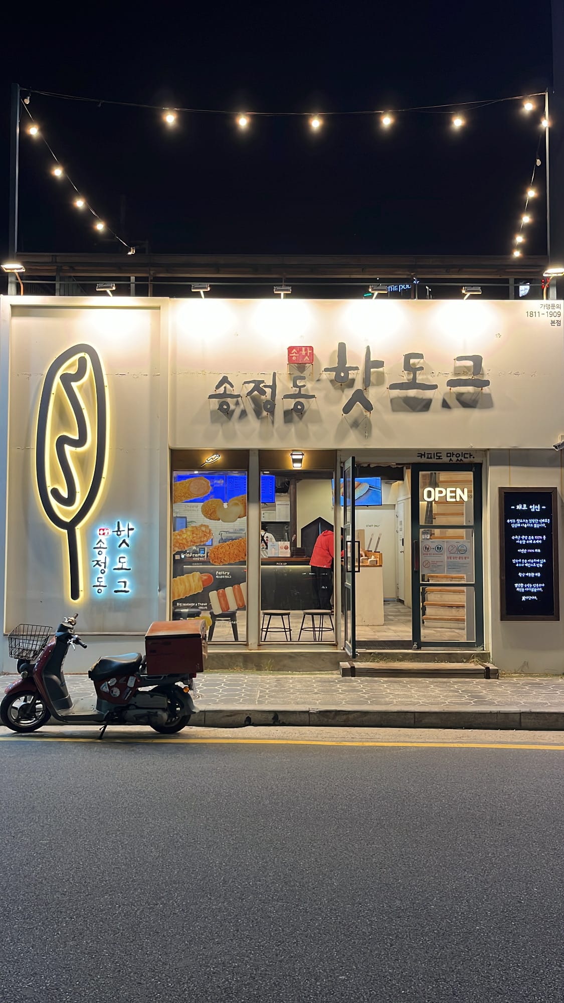 Brightly illuminated storefront of Songjeongdong Hotdog at night